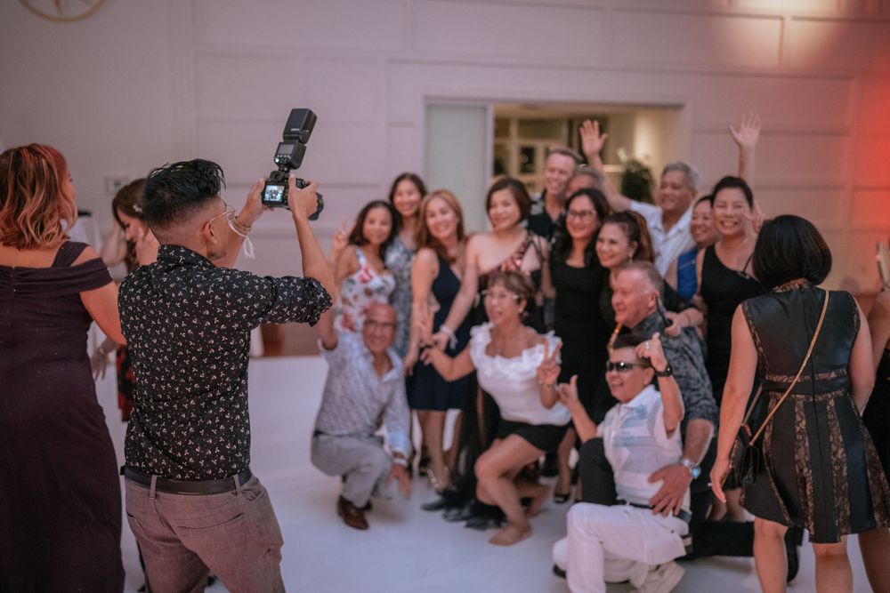 Photographer with a camera captures a group of event attendees gathered together in a bright indoor venue.