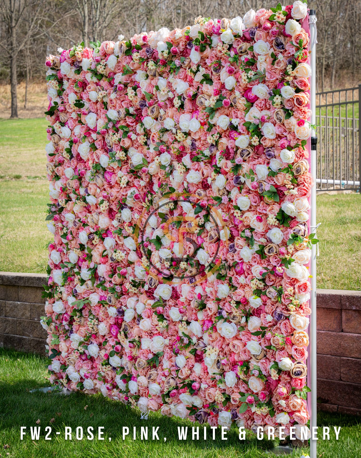 Luxurious pink and white rose wall with circular monogram and green accents.