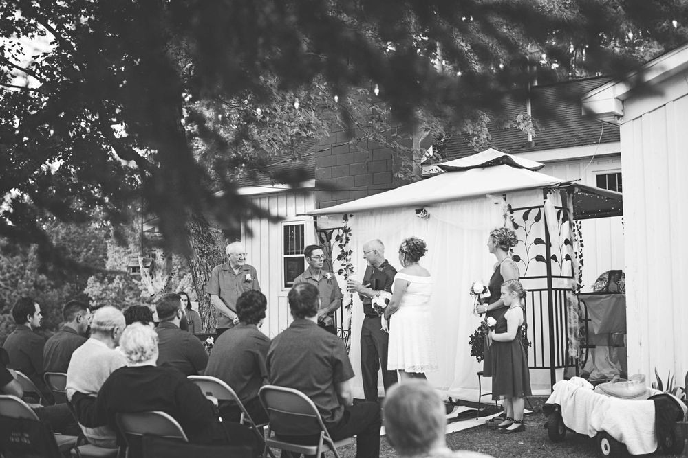 A black and white panoramic photo showing an outdoor gathering with people mingling at what appears to be a social event.