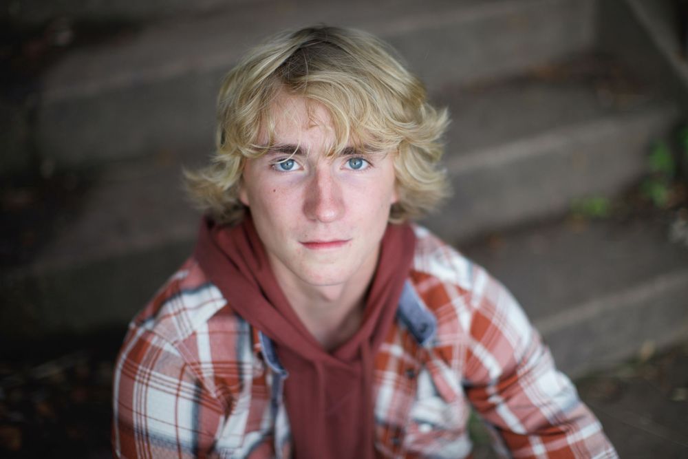 A casual portrait features a person in a plaid flannel shirt and burgundy hoodie looking directly at the camera.