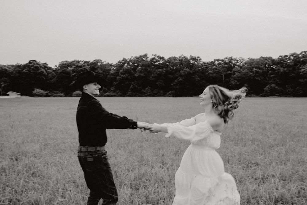 Playful couple's portrait session in a rural field setting with dramatic sky.
