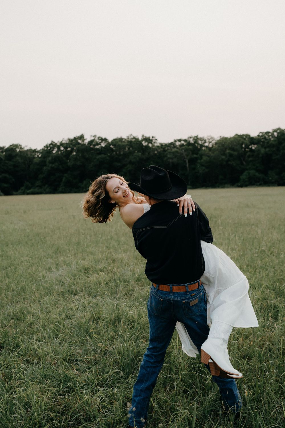 Dancing couple captured in a dramatic dip pose in an open meadow.