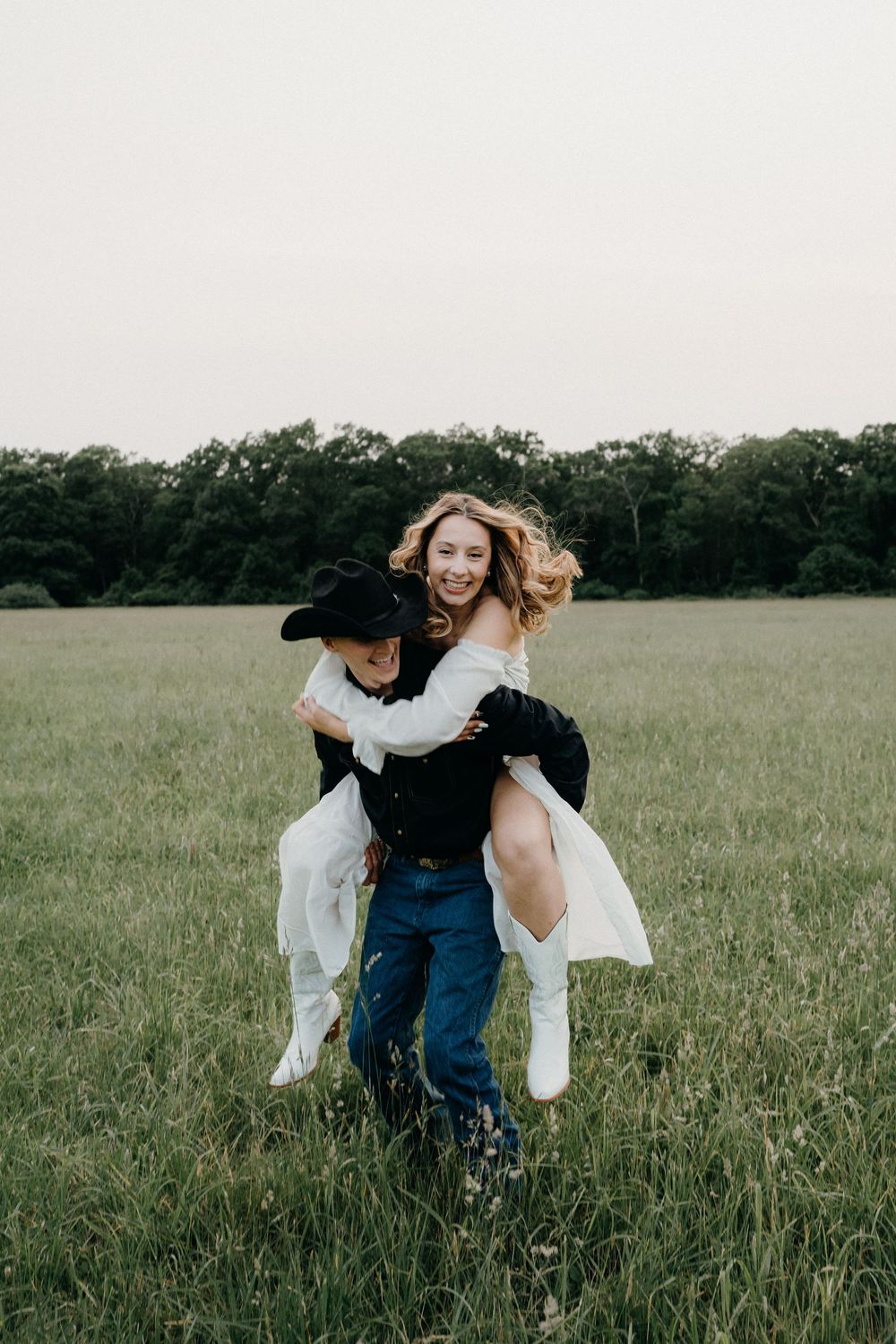 Joyful couple spinning and dancing in a sunlit grassy field.