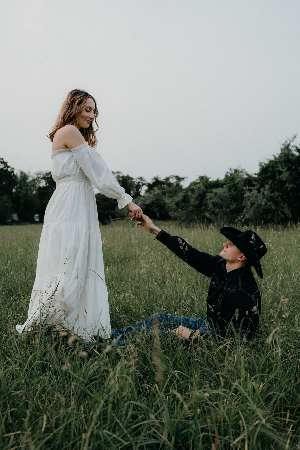Whimsical couple's photoshoot with playful poses in tall grass.