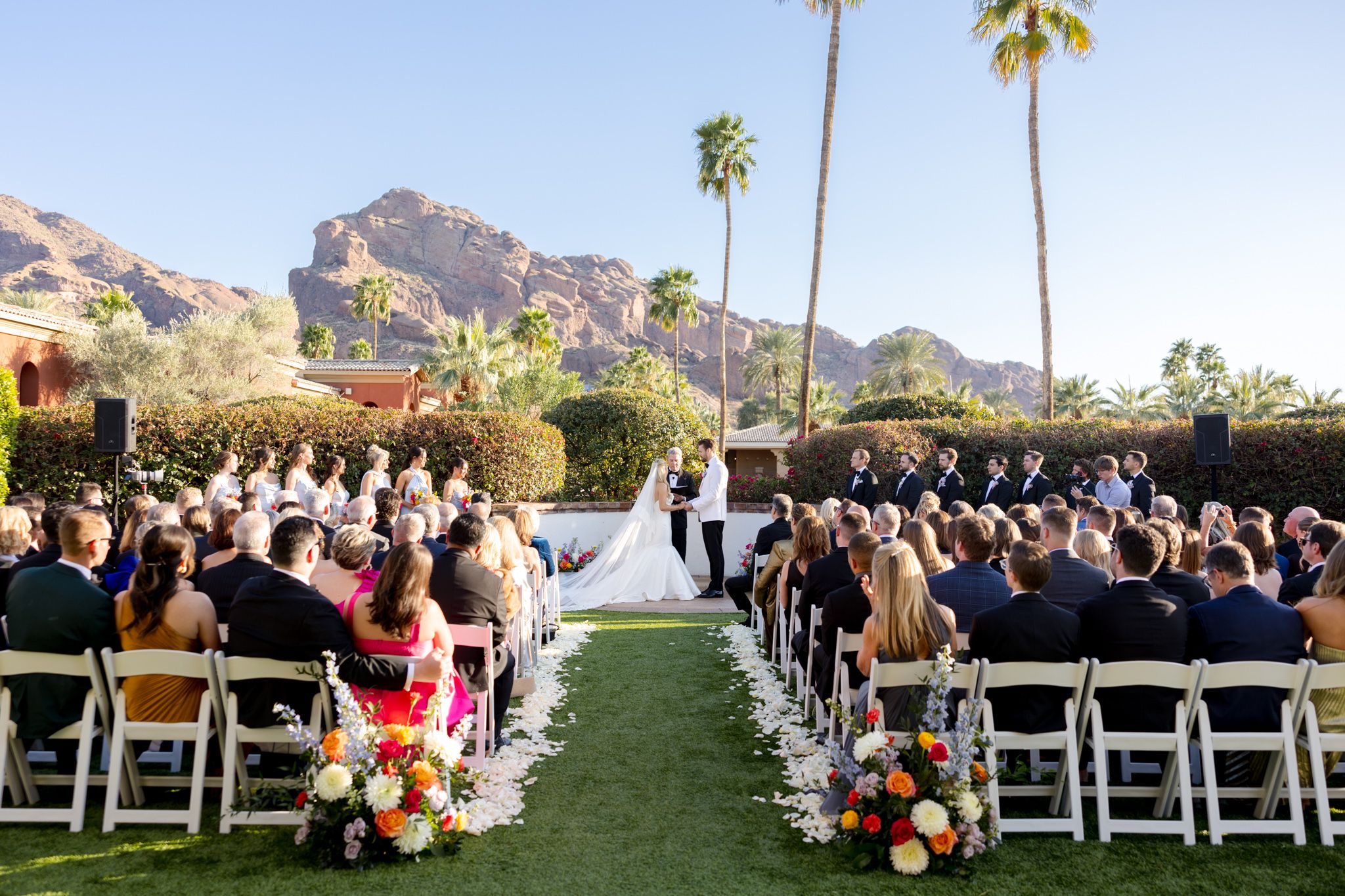 Outdoor wedding ceremony setup with white chairs and floral decor at Omni Montelucia Resort with mountain backdrop.