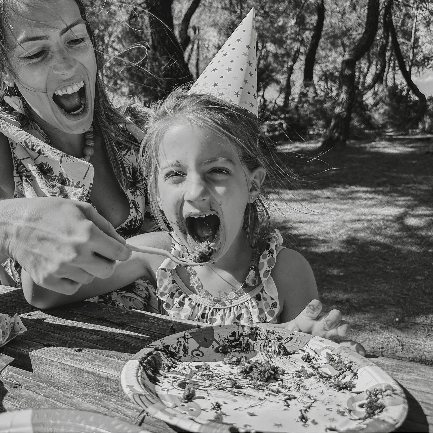 fiesta cumple infantil en parque, verano. mama dando tarta en la boca de la cumpleañera