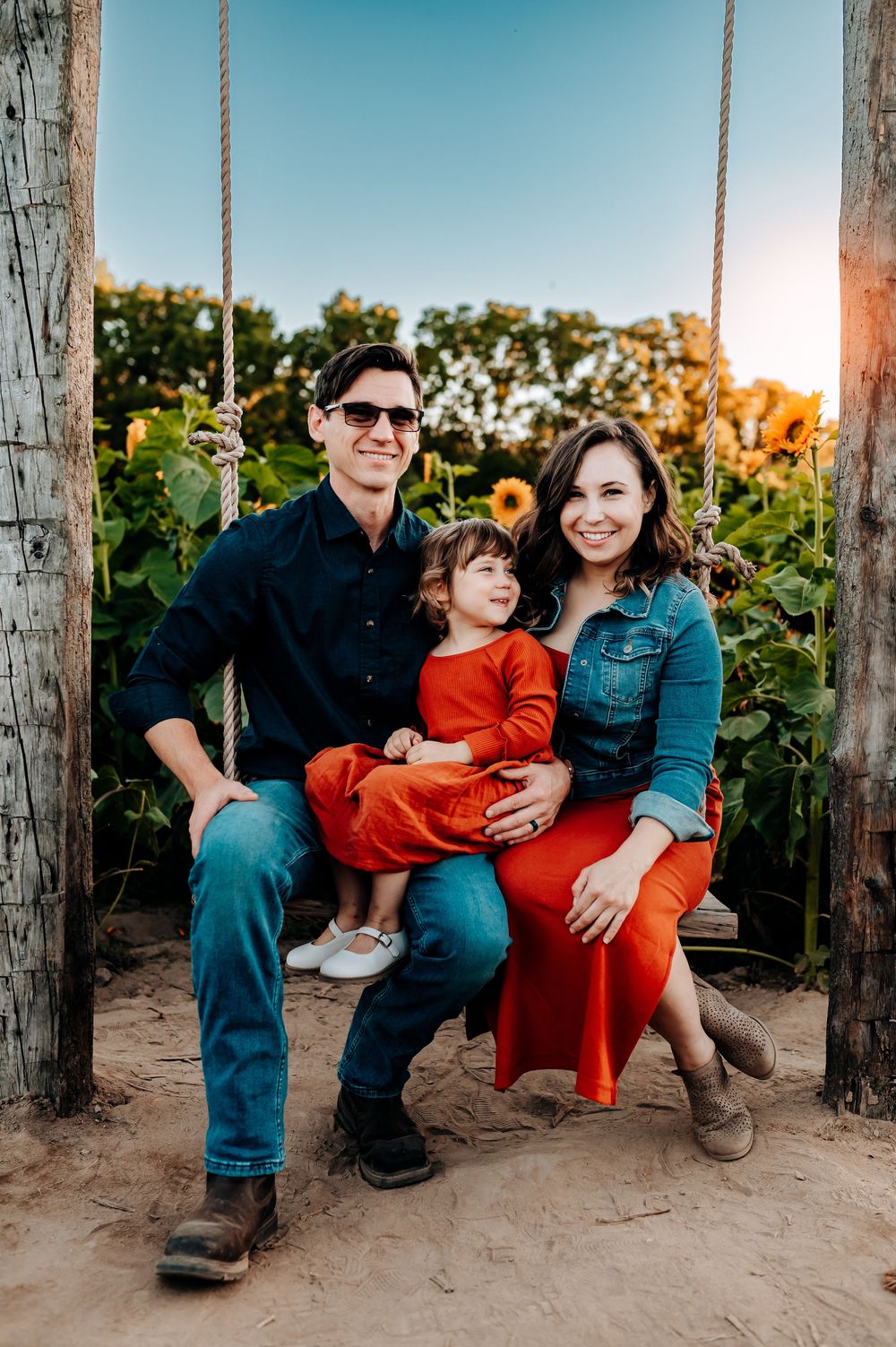 A family sits together on wooden swings at sunset creating a series of candid moments in warm evening light.