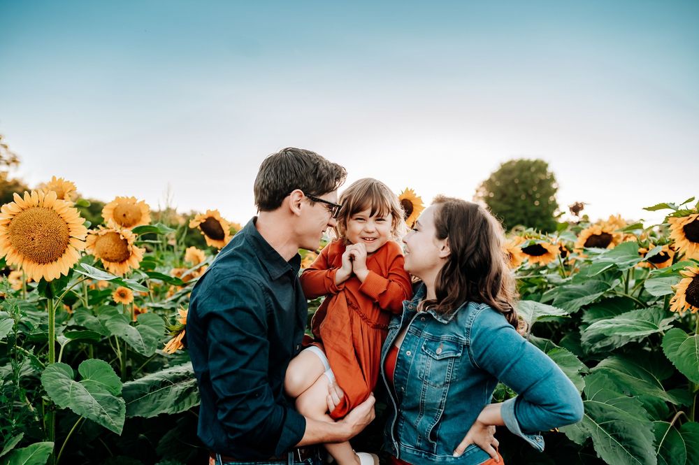A loving family moment captured in a vibrant sunflower field during golden hour.