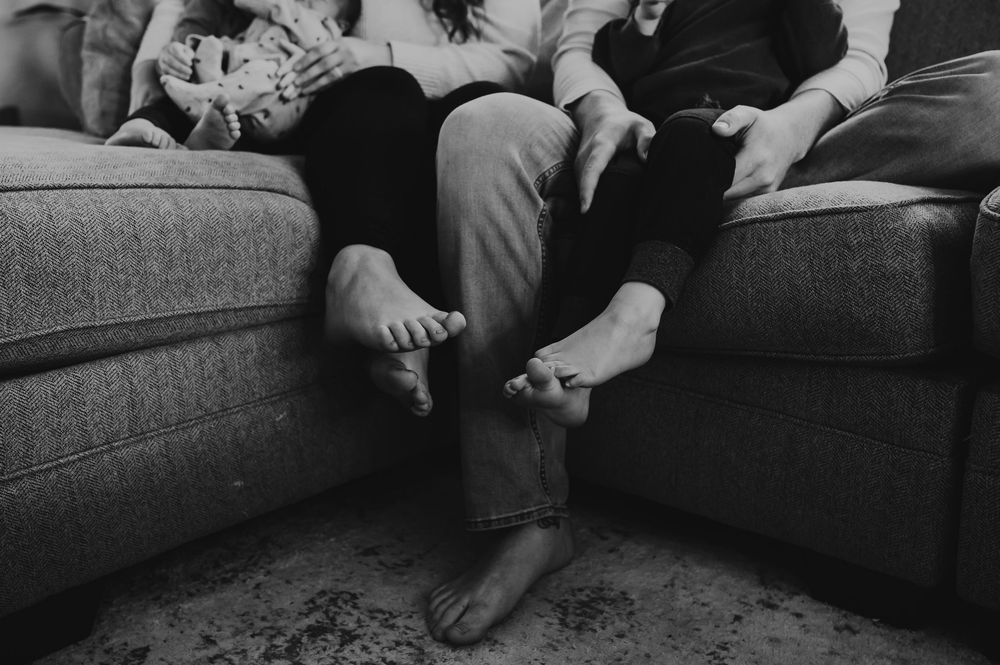 Black and white collage of adults sitting on couches in various casual poses and gestures during social gathering.