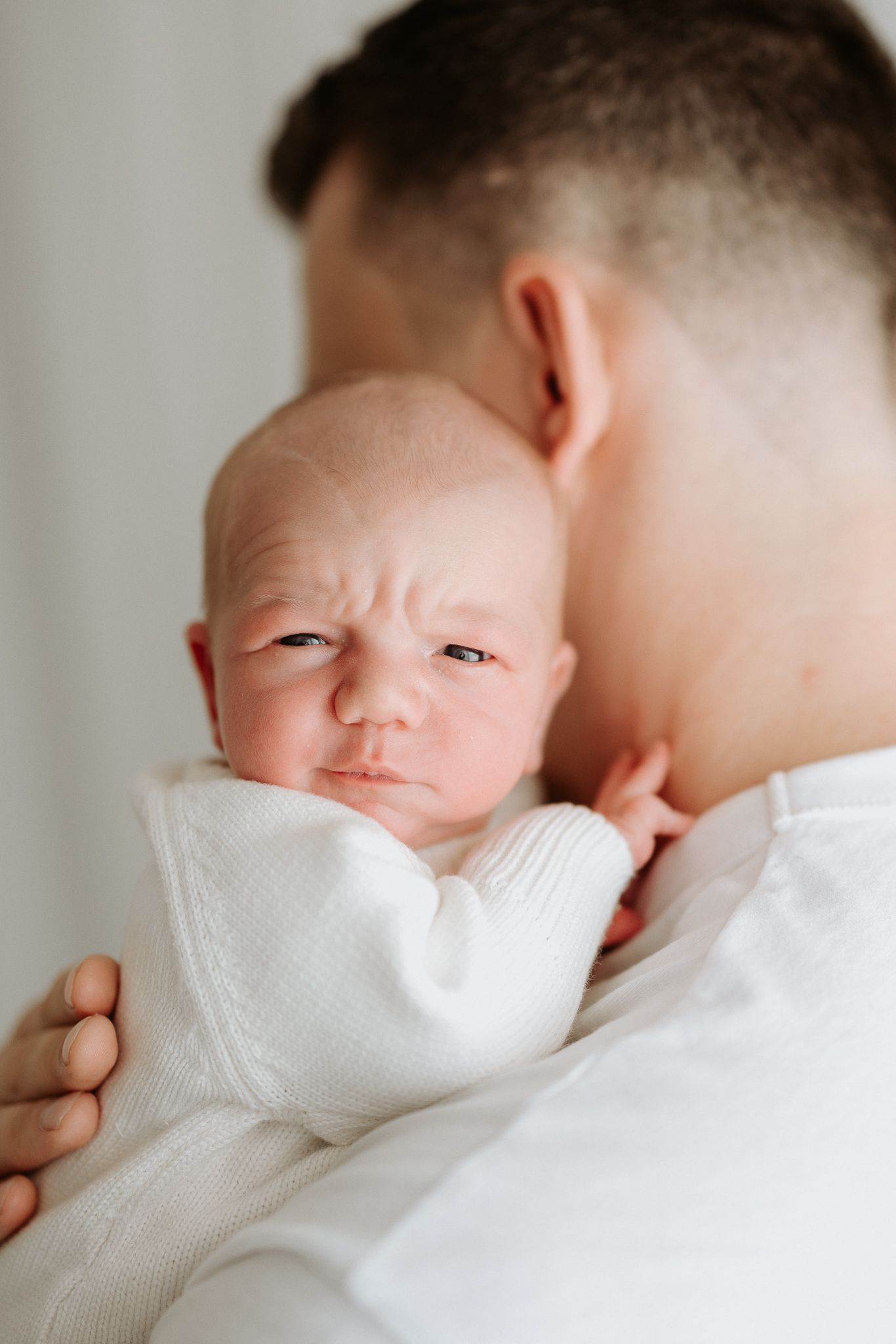 Close-up portrait of newborn baby being held.
