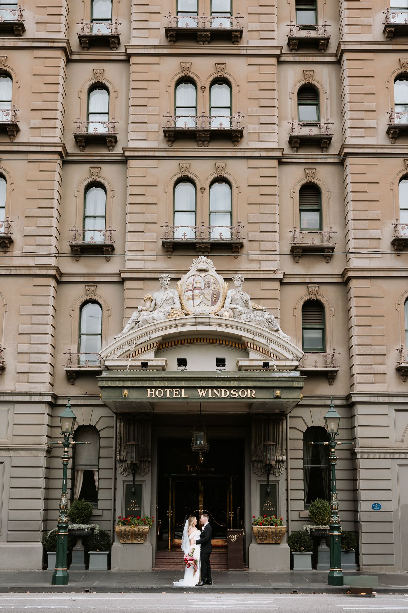 Classic beige stone facade of Hotel Windsor with ornate architectural details and elegant arched entryway in Melbourne.