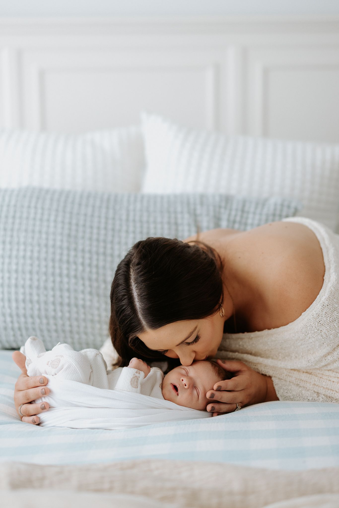 Intimate moment between parent and baby on bed with soft lighting.