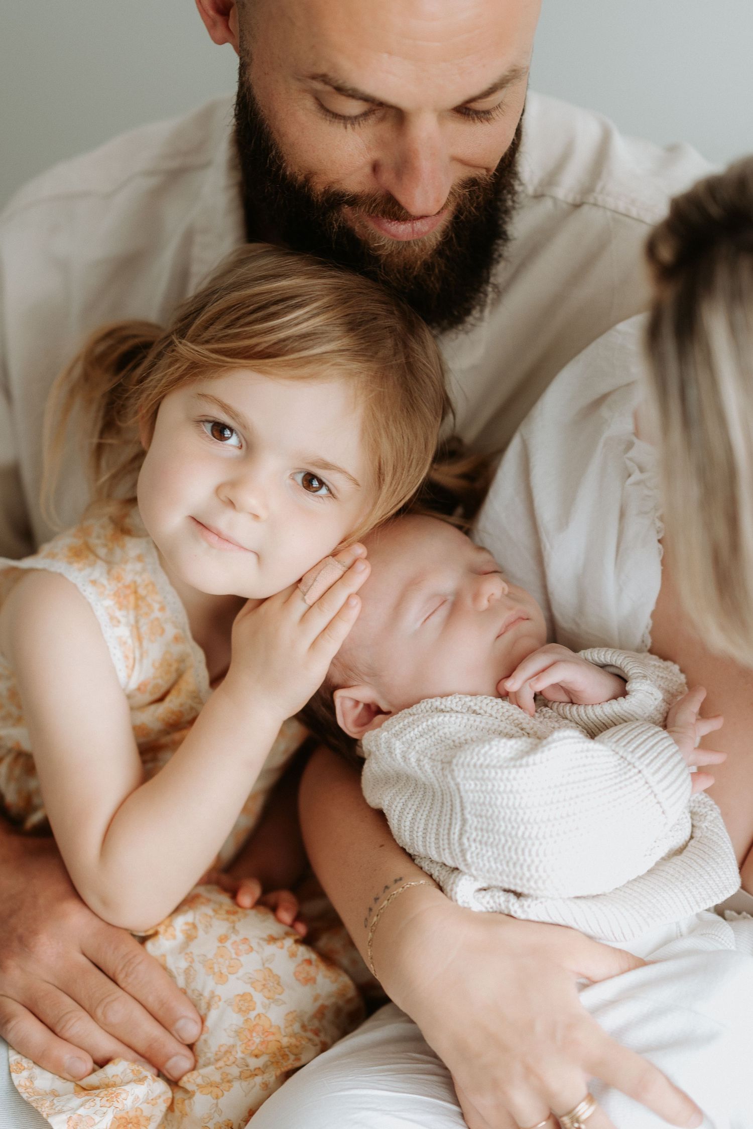 A tender family moment with a sleeping newborn and toddler.