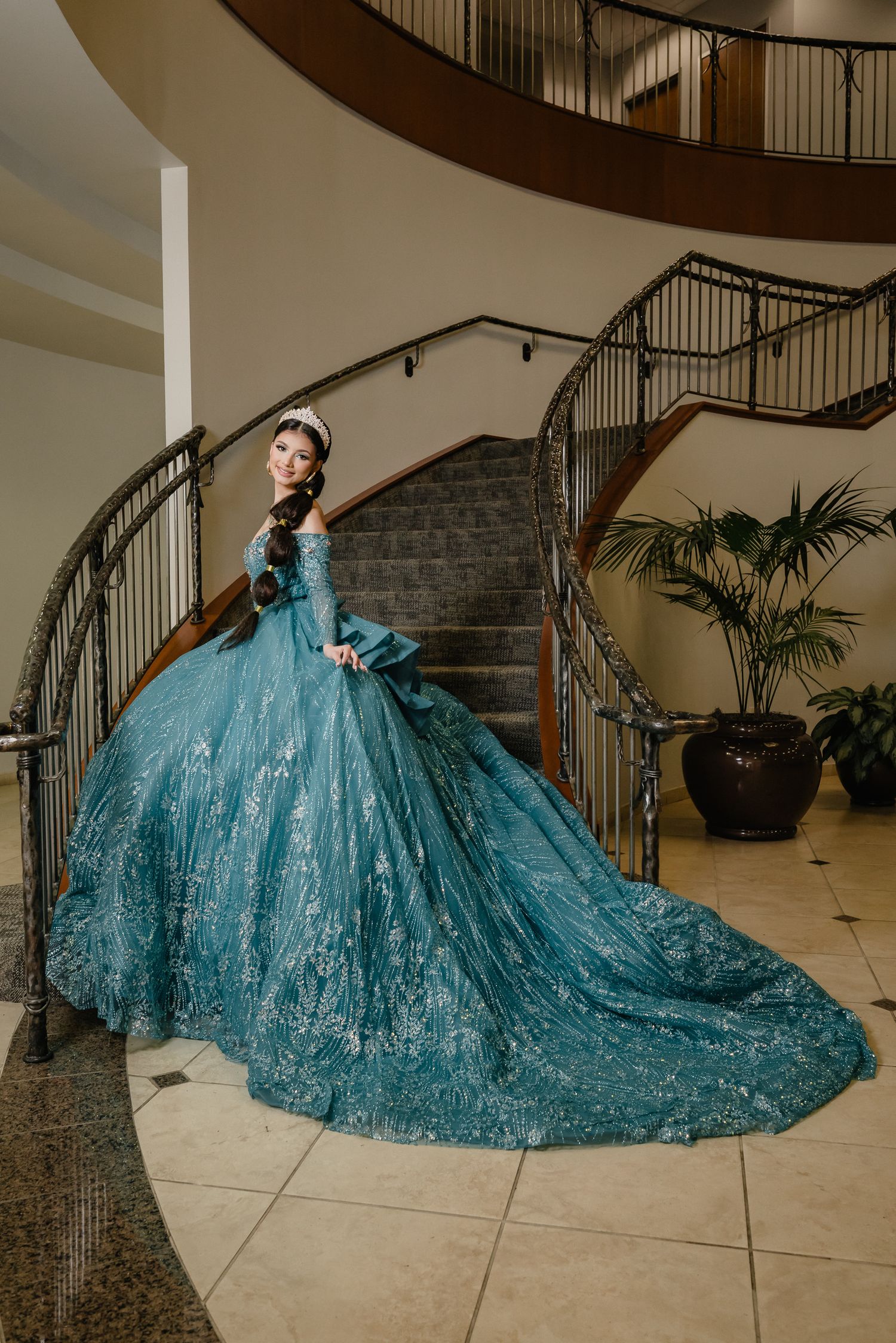 A stunning teal ballgown with intricate detailing and long train photographed on an elegant curved staircase.