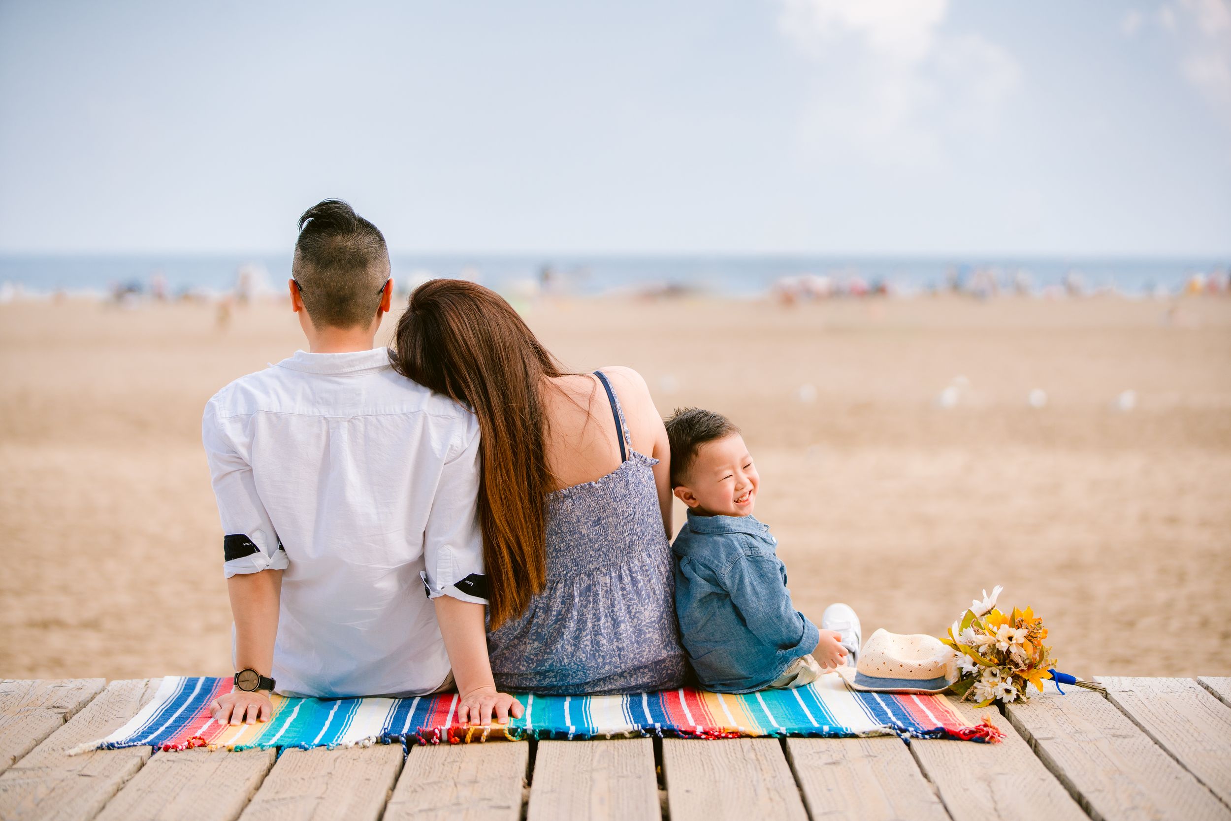 Family sits together on colorful blanket overlooking scenic desert landscape at sunset.