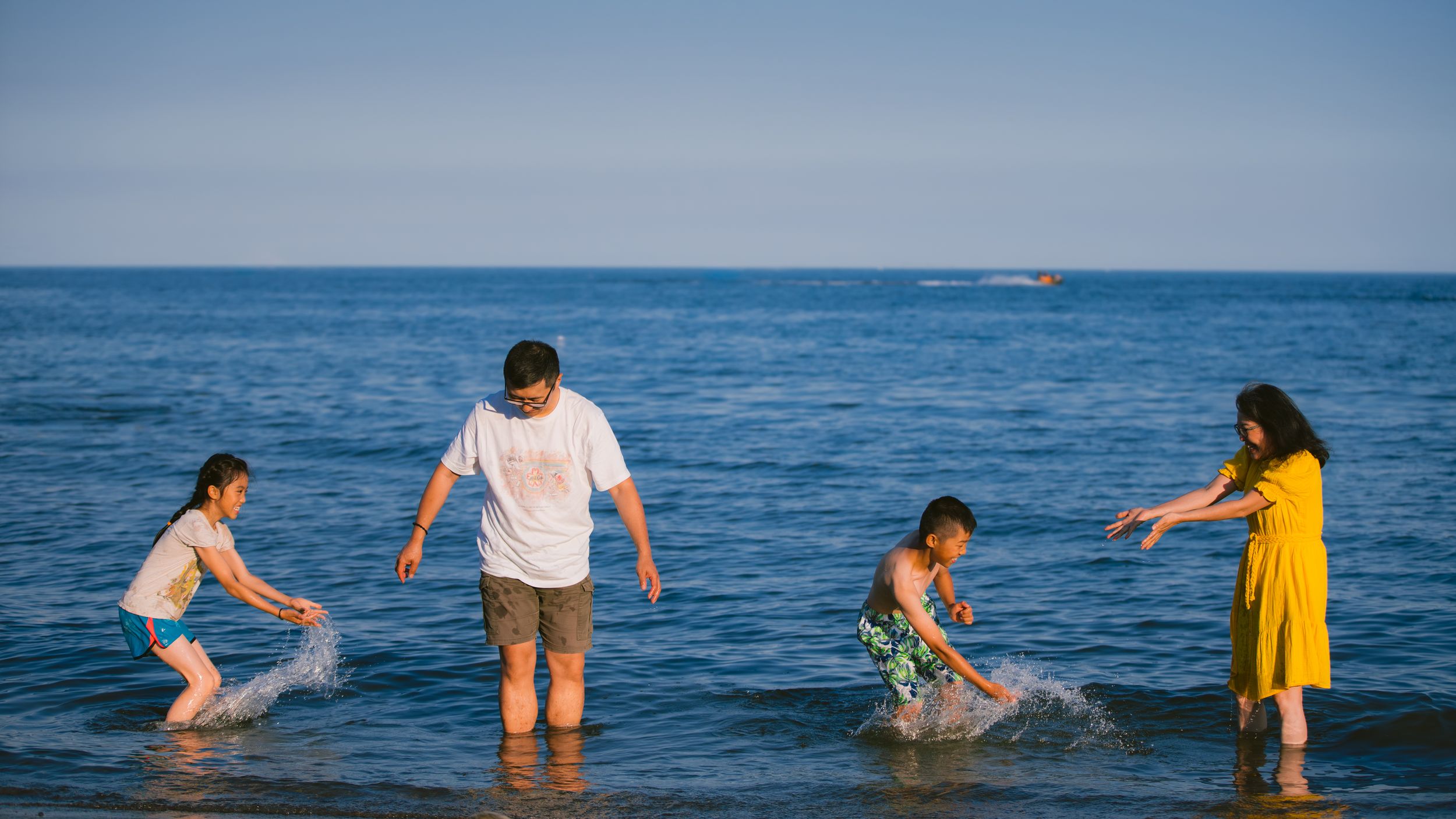 Family playing and splashing together in the blue ocean water on a sunny summer day.