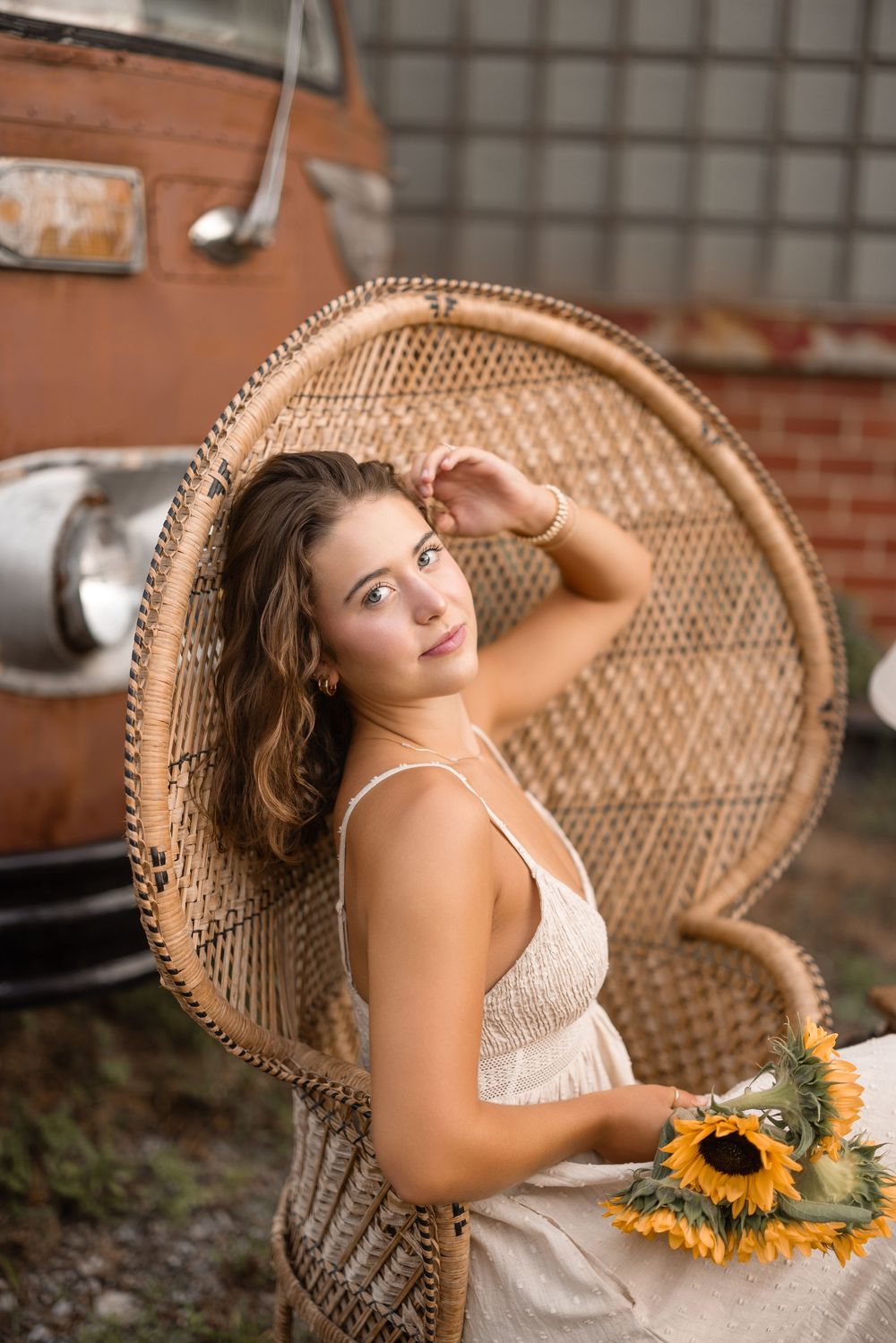 A peaceful scene with a woven peacock chair and sunflowers in an industrial setting with brick walls.