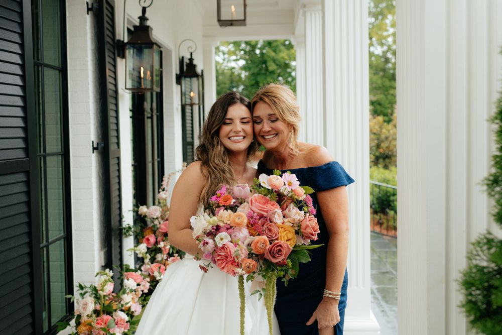 a bride and her mother in law and florist on the front porch of the lumpkin house wedding venue in albertville, alabama