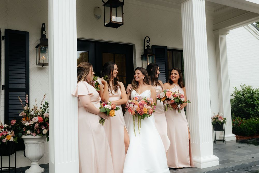 a bride and her bridesmaids on the front porch of the lumpkin house wedding venue in albertville, alabama