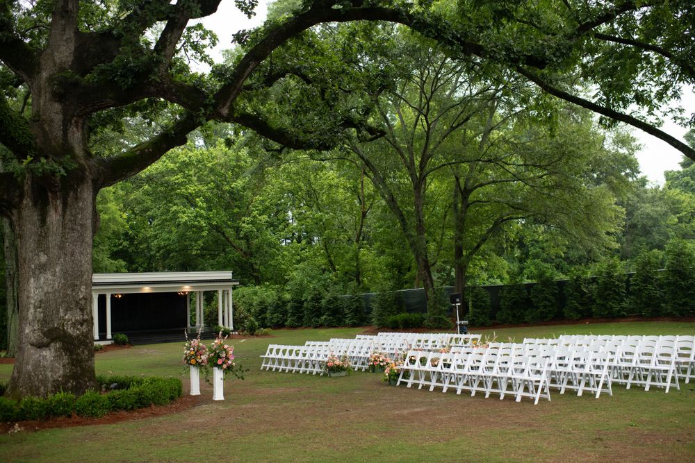 a view of a rainy wedding ceremony set up under a live oak in the backyard of the lumpkin house wedding venue, in albertville, alabama.