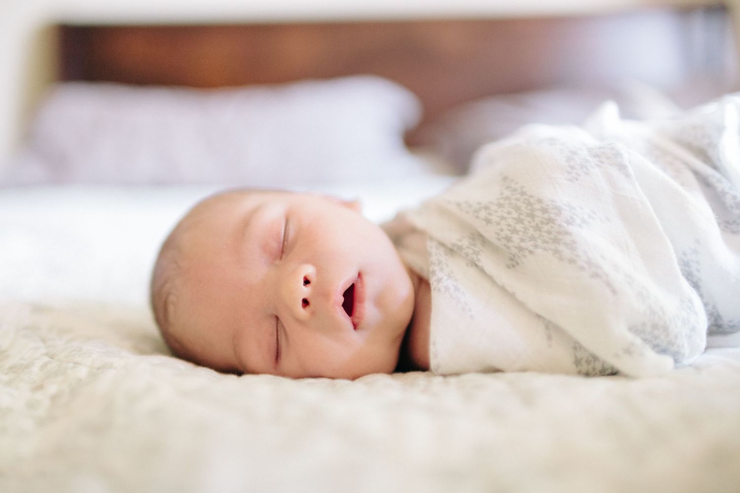 sleeping newborn swaddled on a bed