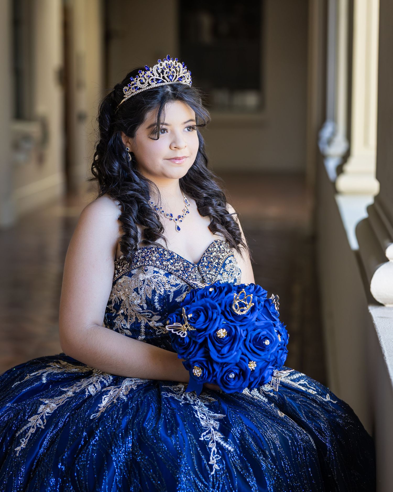 Quinceañera dress in royal blue and silver with a flowing ball gown silhouette and ornate embellishments.