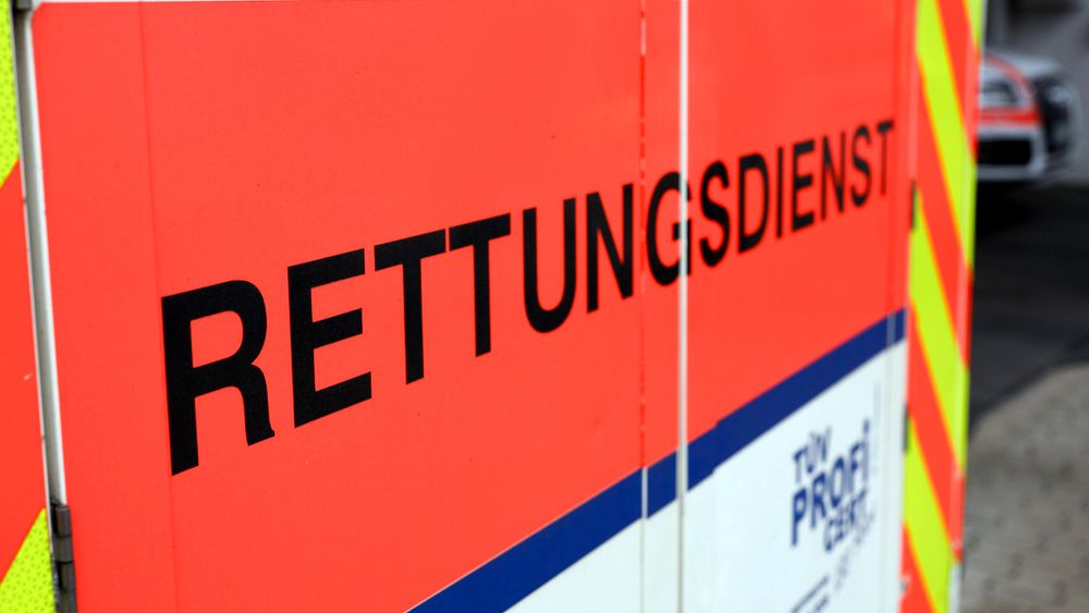 Close-up view of red emergency rescue vehicle with German text 'RETTUNGSDIENST' in black letters and reflective stripes.