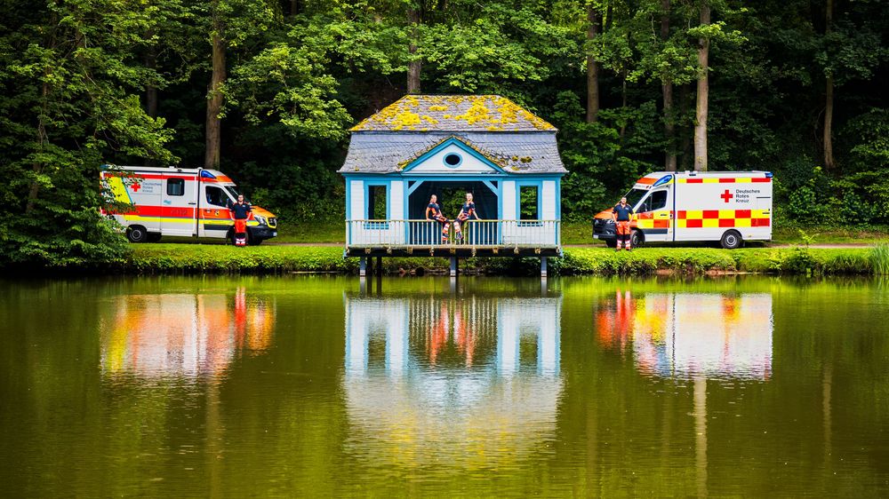 Einsatzfahrzeuge Rettungswagen Deutsches Rotes Kreuz am Schlossteich in Bad Arolsen mit Spiegelung im Wasser und Besatzung