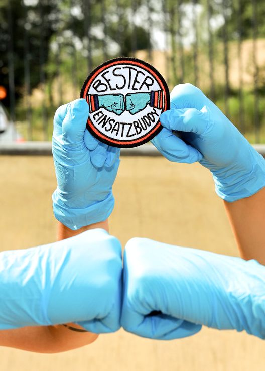 Hände mit medizinischen Handschuhen und Aufneher Button Best Einsatzbudies Deutsches Rotes Kreuz Korbach Bad Arolsen
