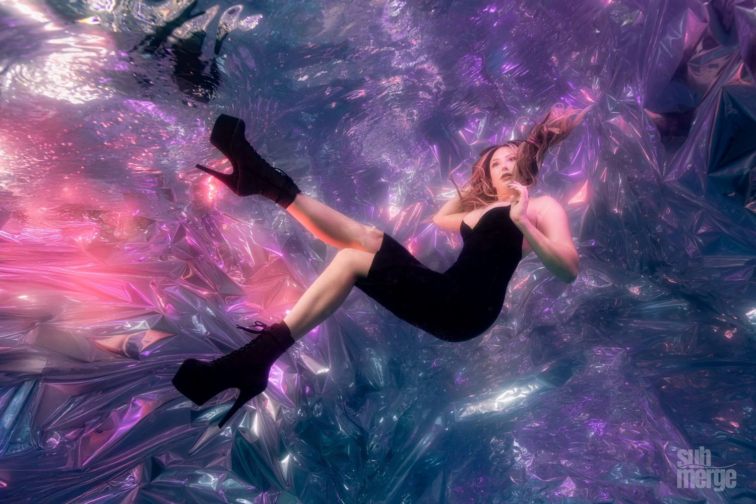 Silhouette figure floating underwater surrounded by ethereal purple and pink light effects creating a dreamy atmosphere.