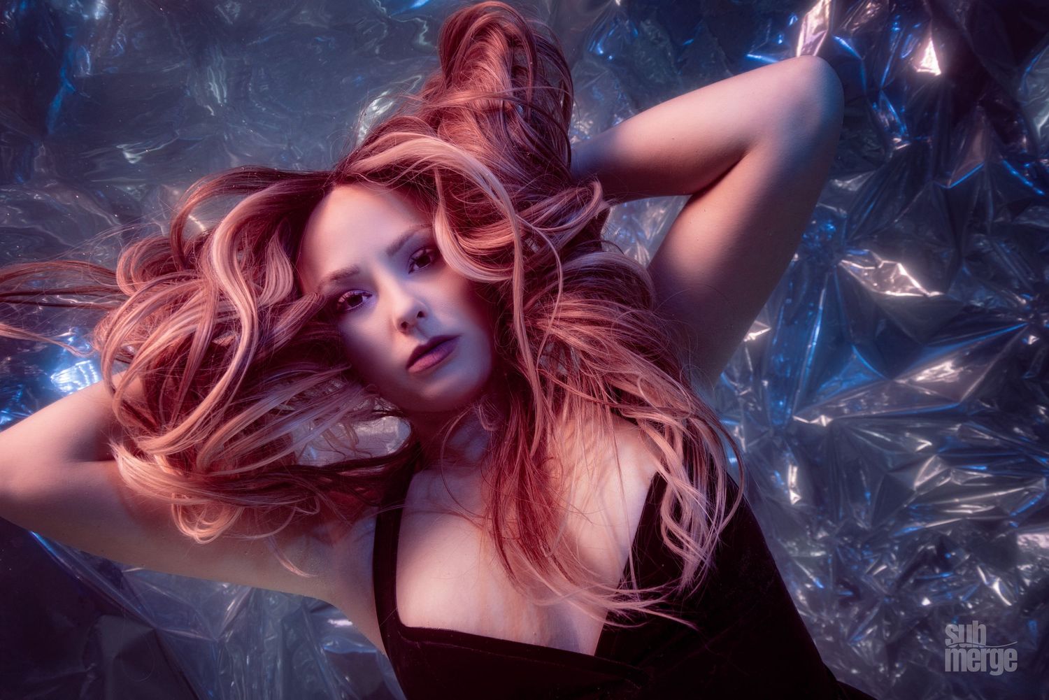 Woman with flowing red hair in artistic portrait with swirling blue magical effects and stars in dark setting.