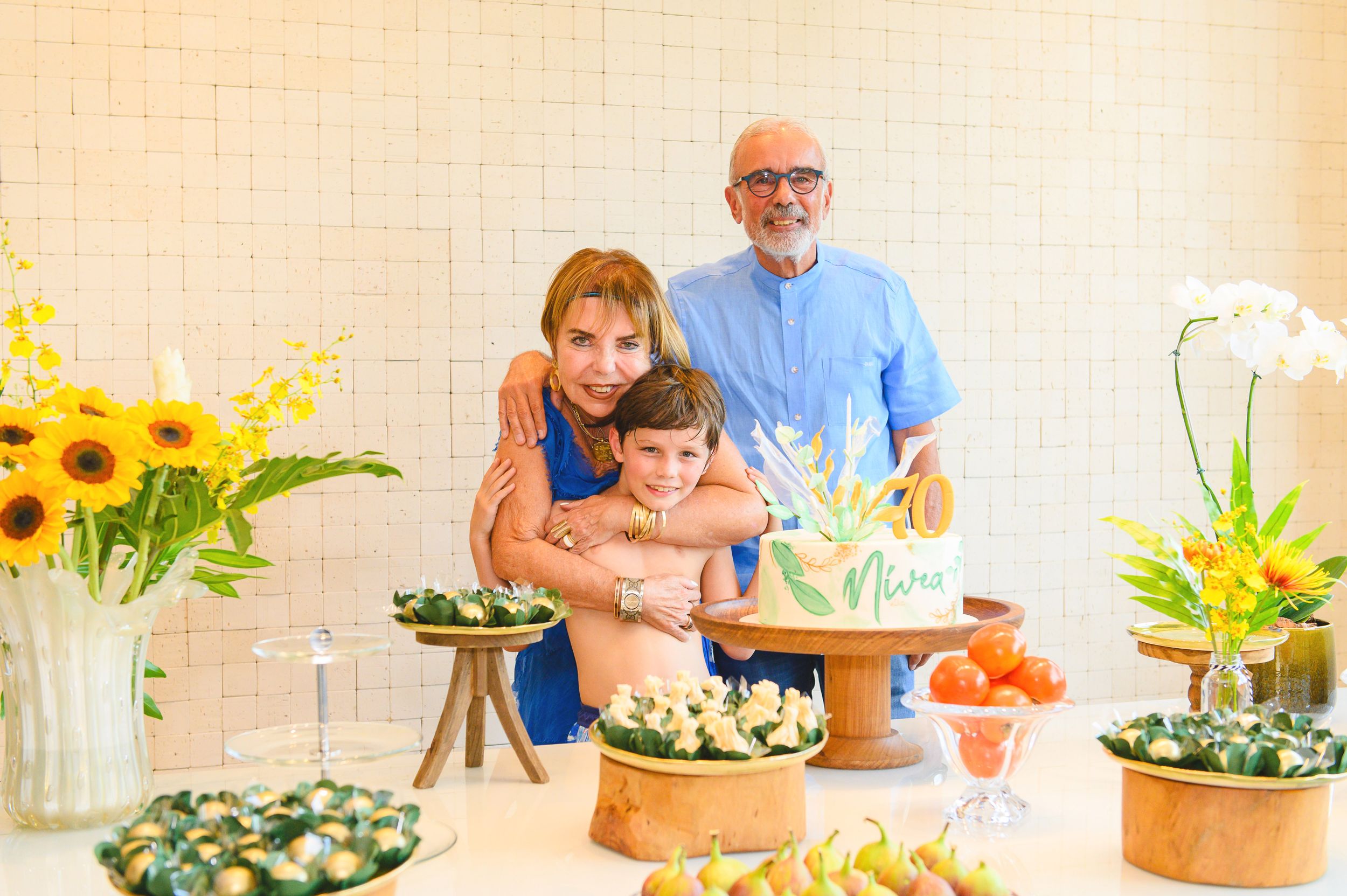 Family enjoying a special celebration by a table decorated with sunflowers, food platters and floral arrangements.