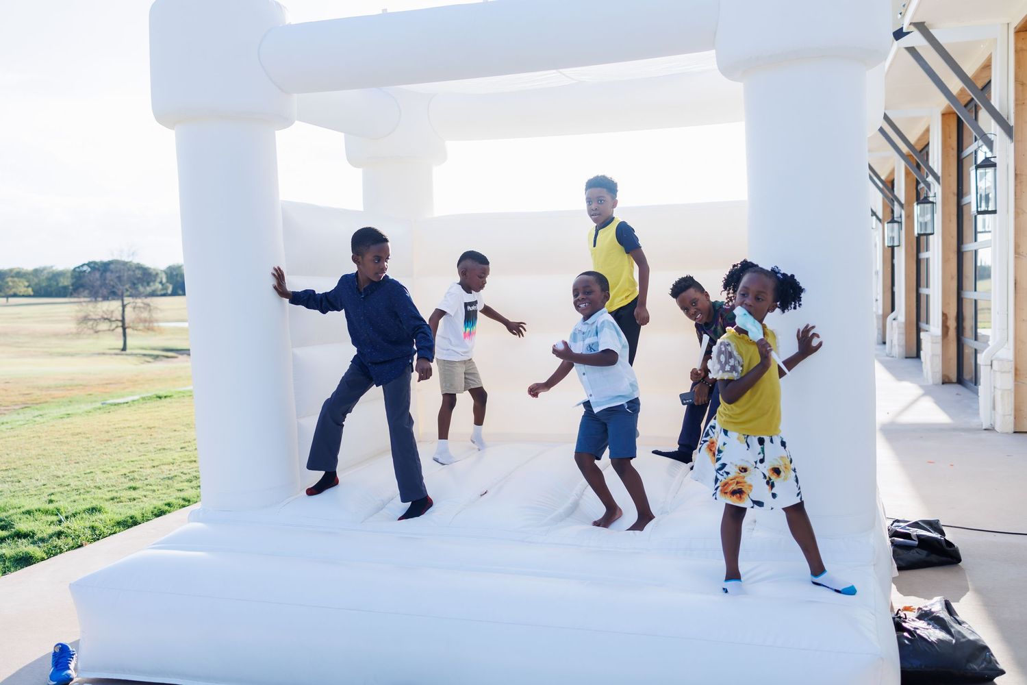 Children playing and jumping in a white inflatable bounce house at Bella Cavalli for a first birthday party