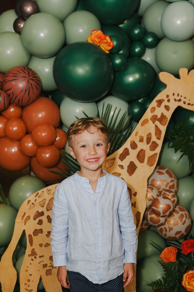 Candid joy—young guest smiling beside a safari-themed balloon wall during a luxury baby shower in Manhattan’s Financial District.