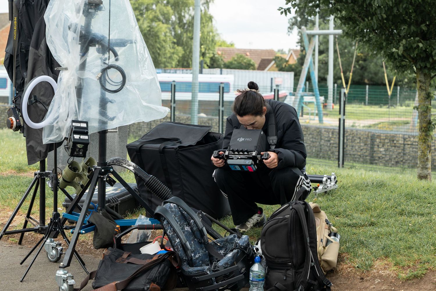 Camera operator sits at workstation with video equipment and monitors set up outdoors on location for filming.
