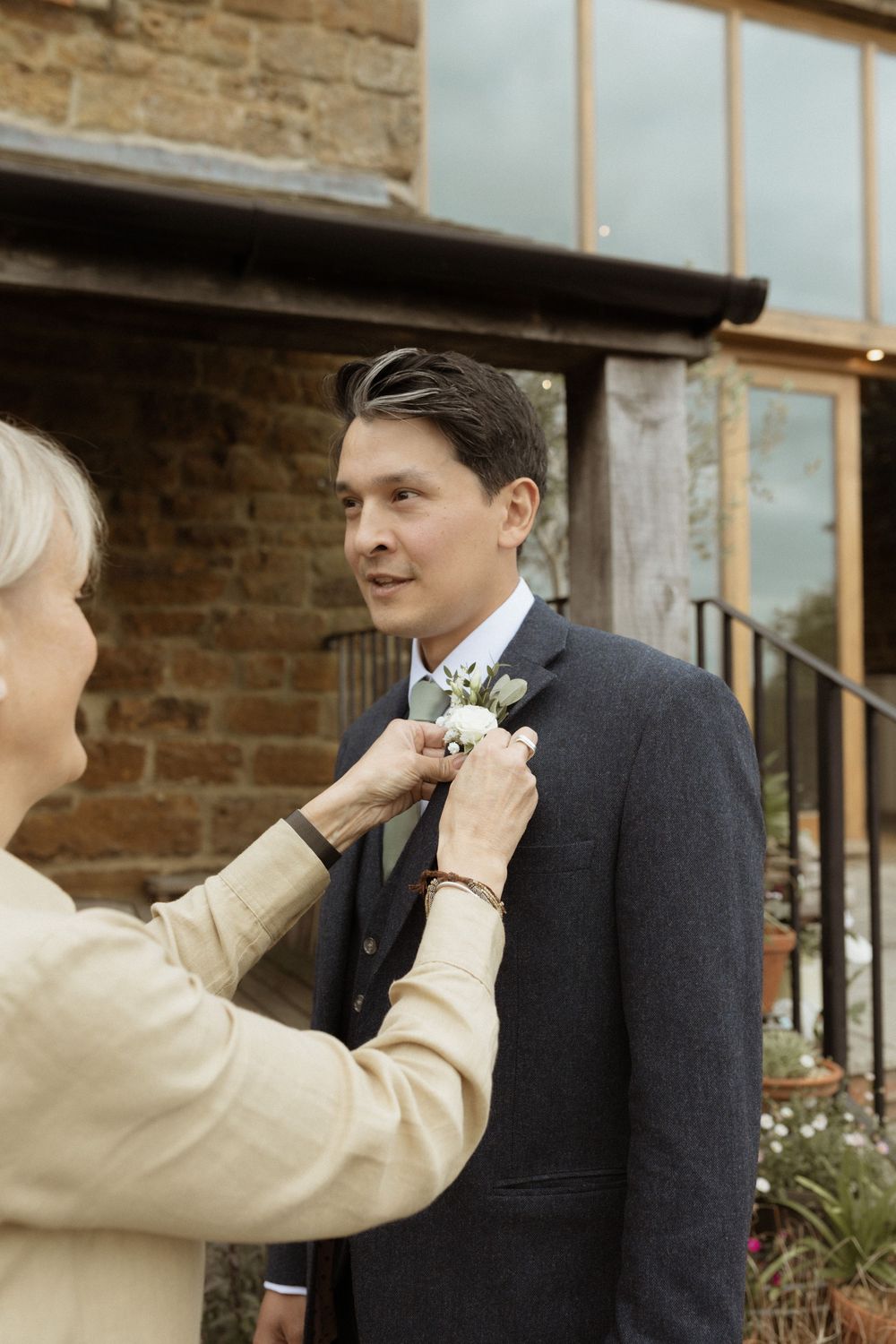 Someone having a boutonniere pinned to their dark suit jacket at Crockwell Farm wedding
