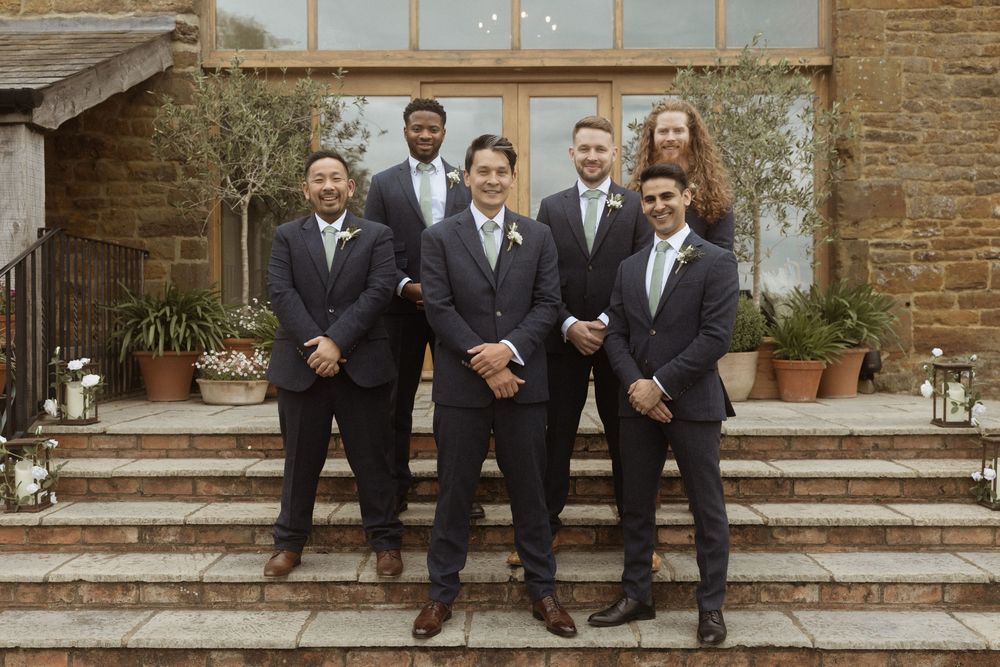 A wedding party of groomsmen in dark suits pose together at Crockwell Farm wedding