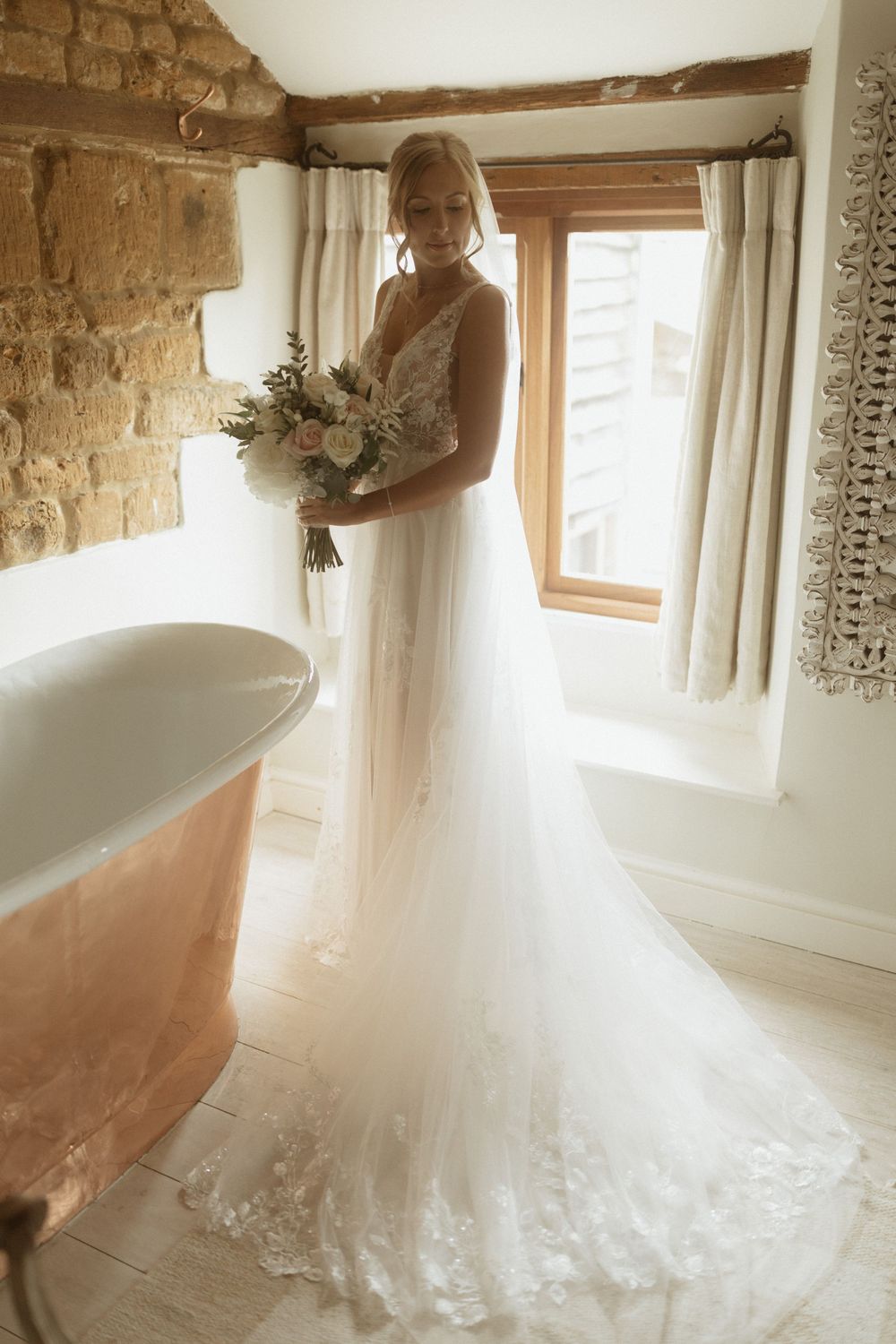 A bride in a flowing white lace gown holds a bouquet at Crockwell Farm wedding