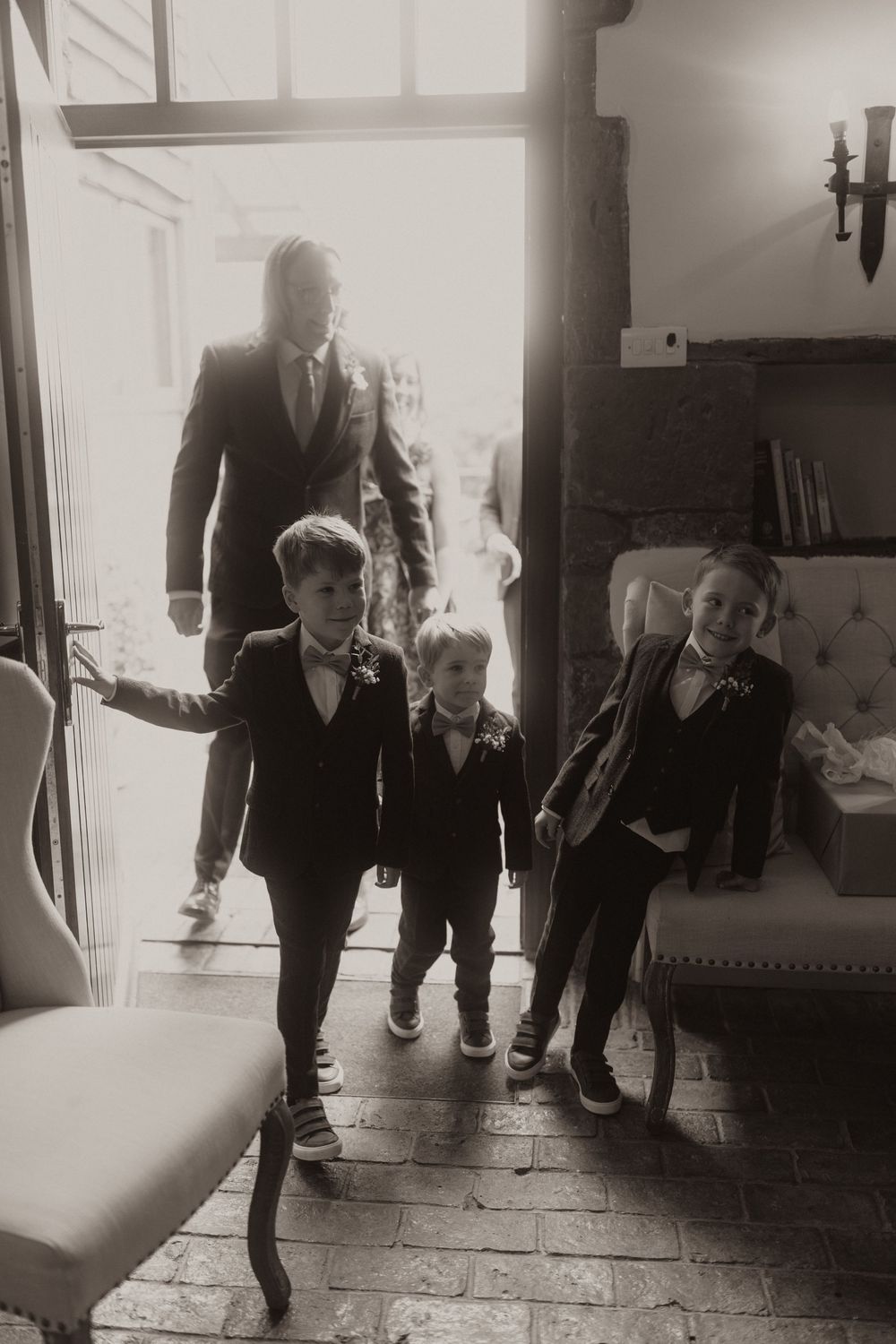 Black and white photo showing children in formal attire walking through an elegant doorwayat Crockwell Farm wedding