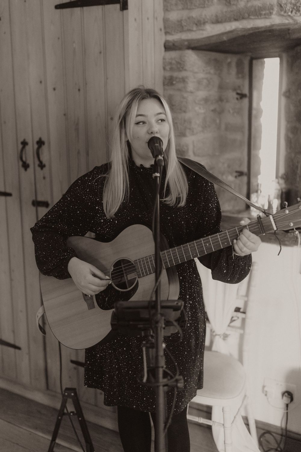 Black and white photo of musician performing with acoustic guitar at Crockwell Farm wedding