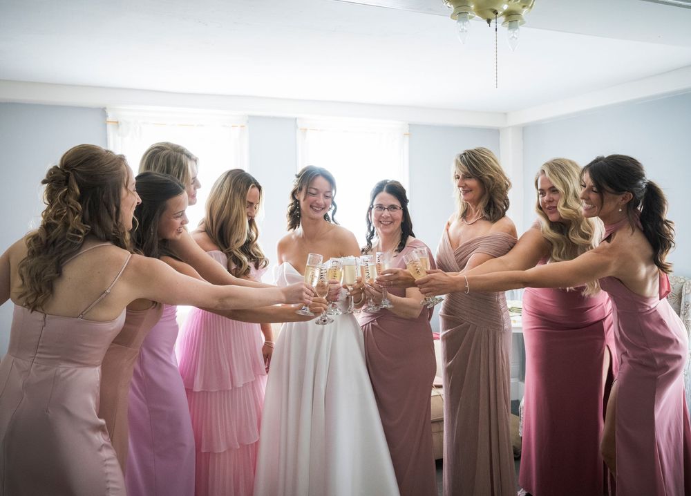 Bridesmaids wearing pink dresses toast together in celebration from multiple angles at a wedding event.