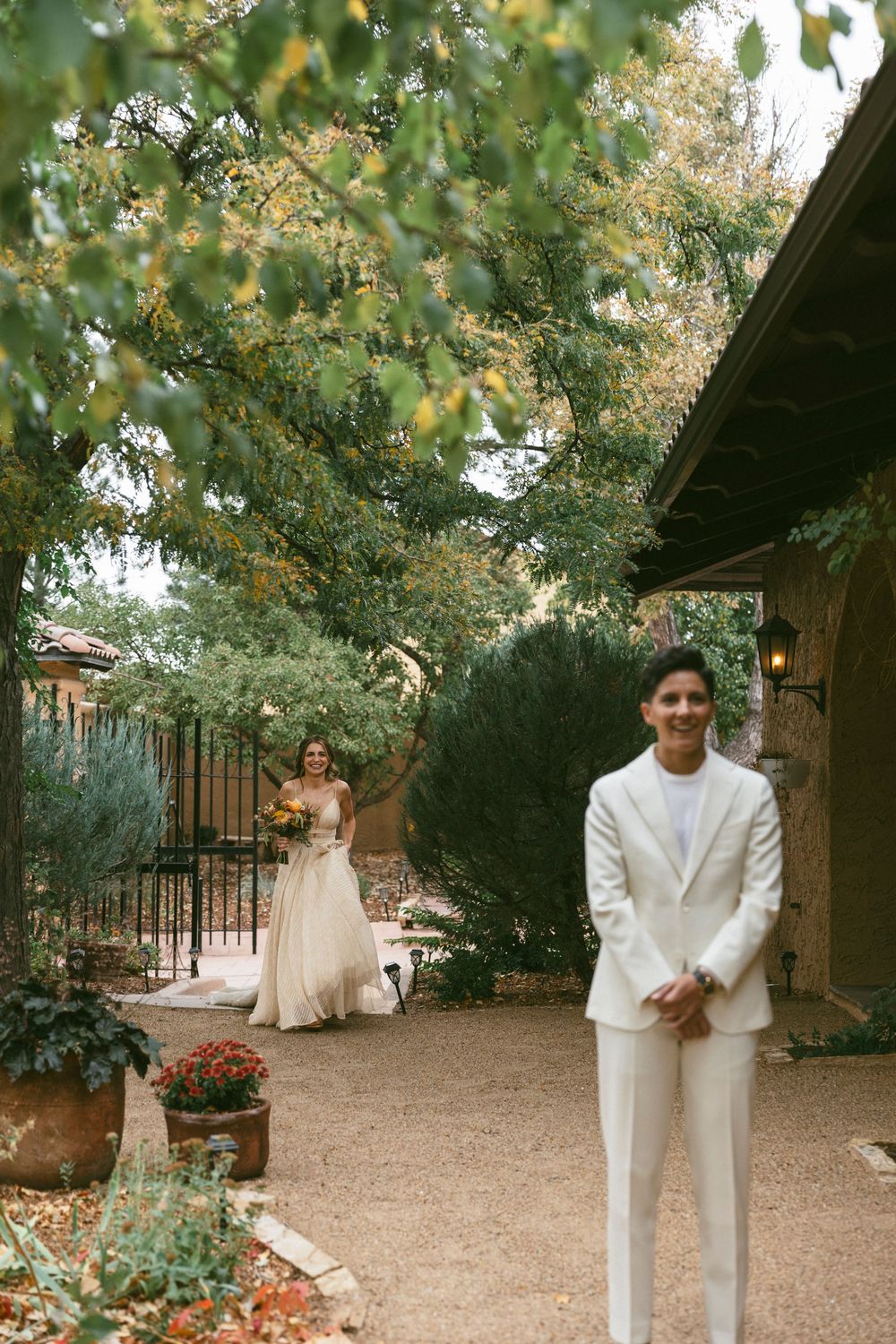 A first look wedding photo in a garden setting with a white suit and flowing dress among lush greenery at villa parker