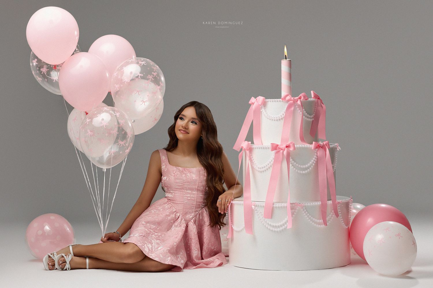 Elegant pink and white birthday setup with decorative cake, balloons and soft celebratory styling against gray backdrop for 13th birthday