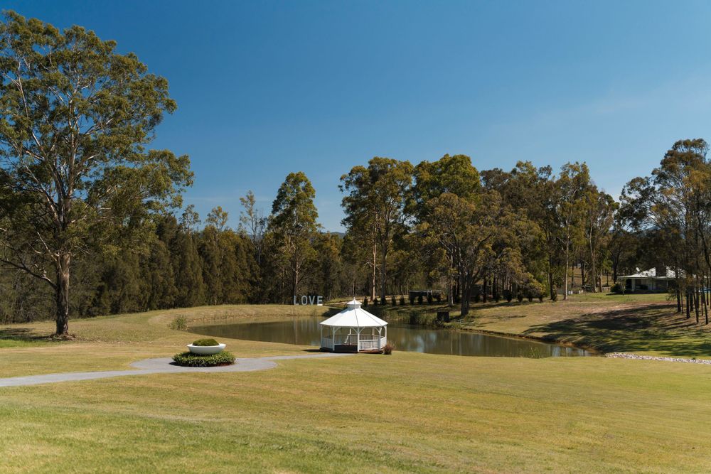 A white gazebo stands on a manicured golf course surrounded by tall eucalyptus trees on a sunny day.