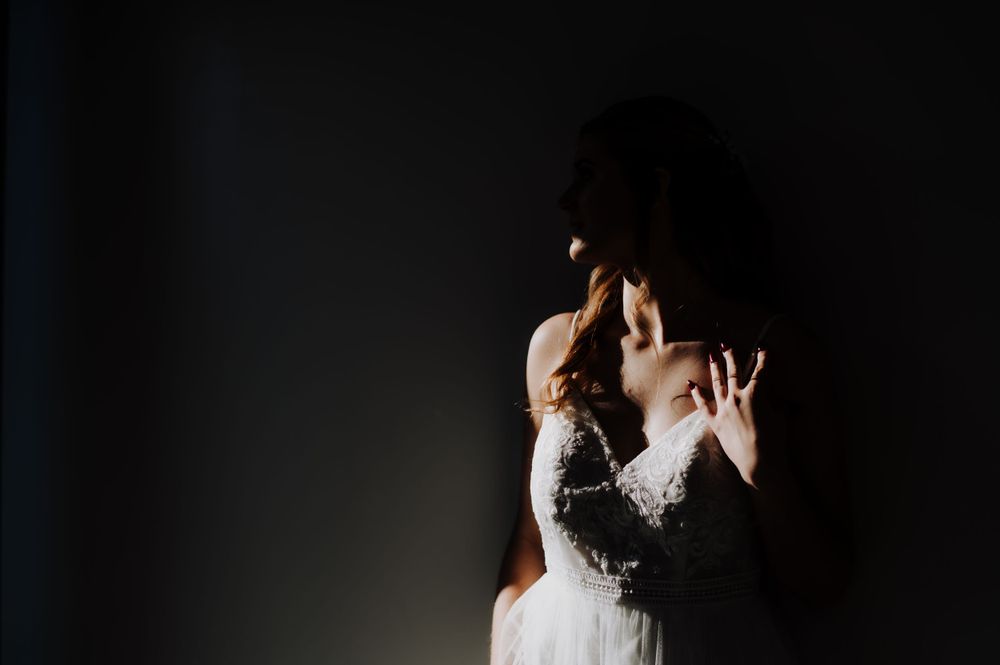 Dramatic lighting captures a silhouette of a bride in her wedding dress.