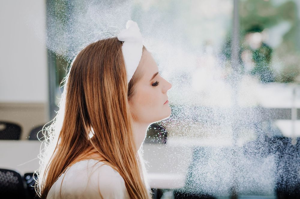 Ethereal bridal beauty shot with hairspray mist creating dreamy effect.
