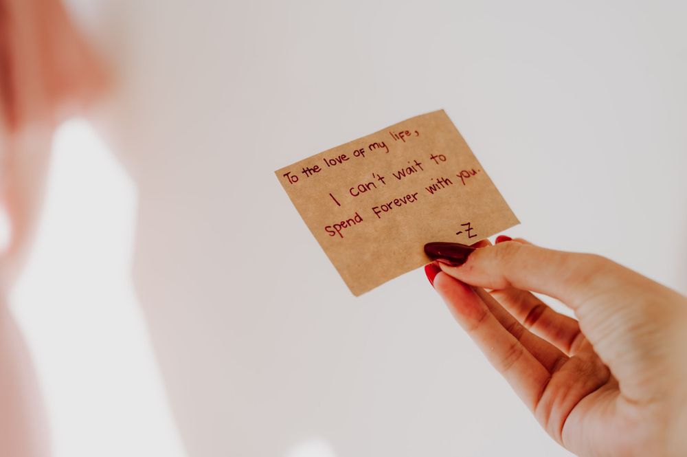 Hand holding handwritten note on kraft paper against white background.