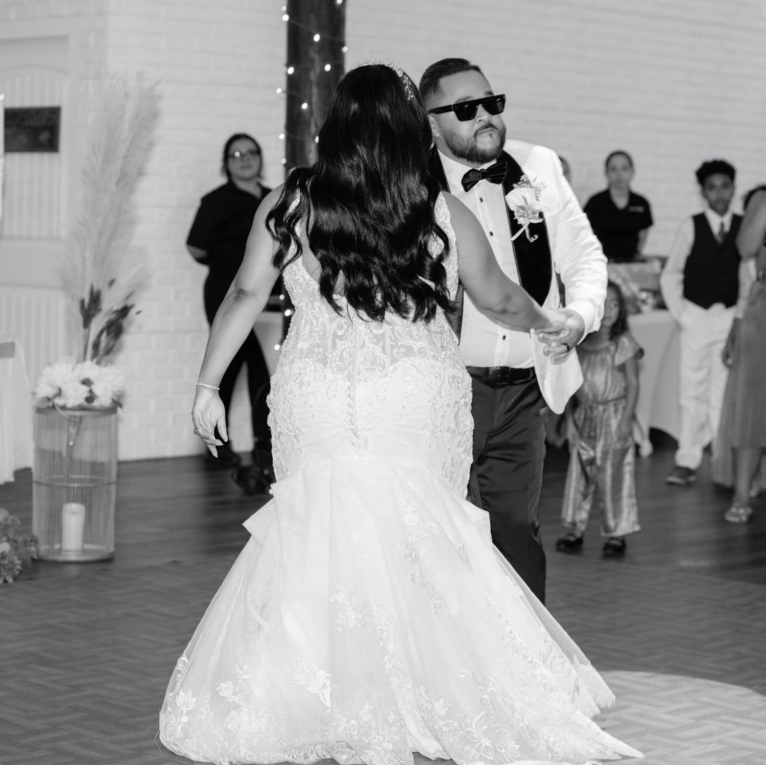 Wedding couple dancing together in monochrome on indoor dance floor.