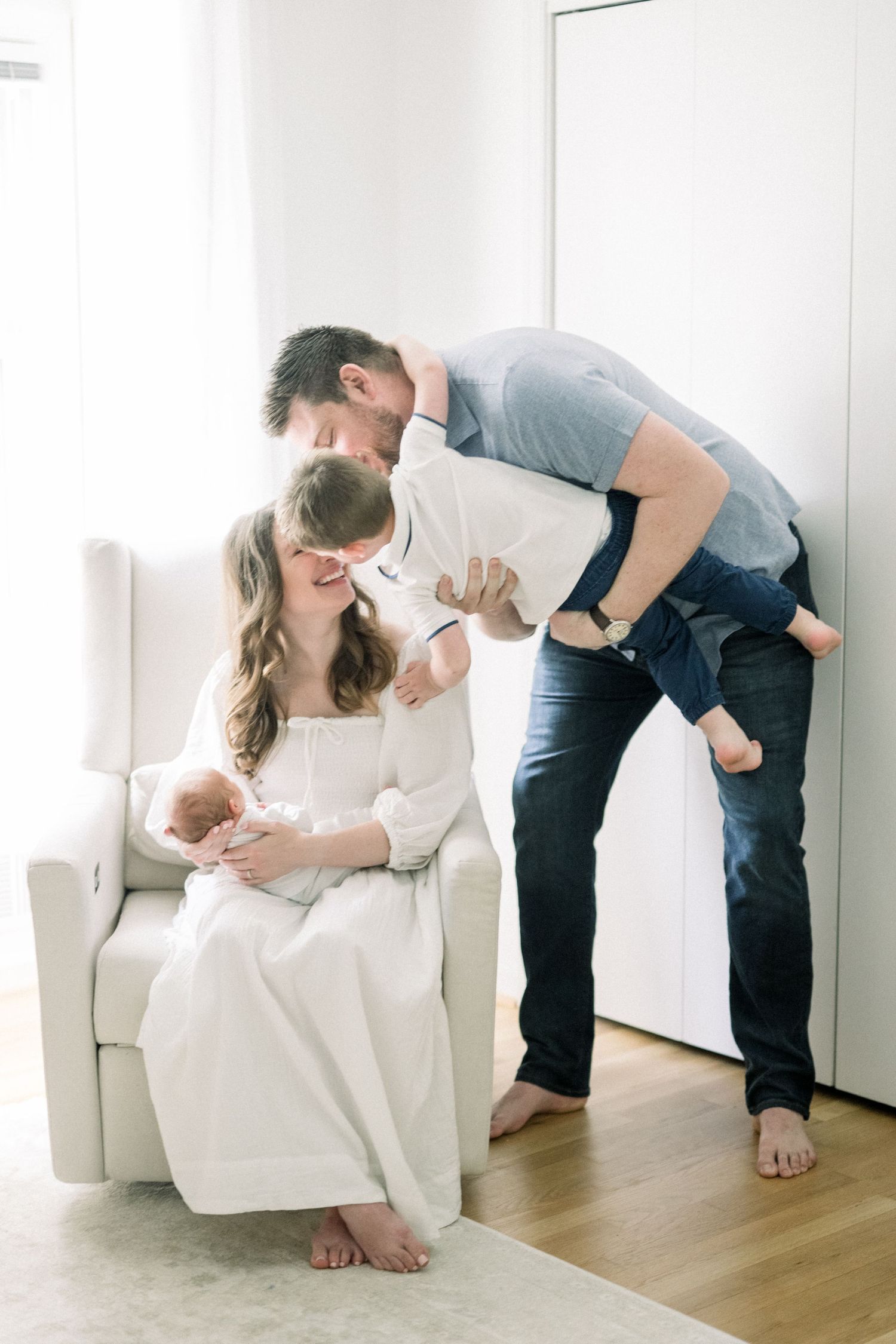 A photo series shows adults interacting with a baby on a white armchair in a bright, minimalist interior setting.