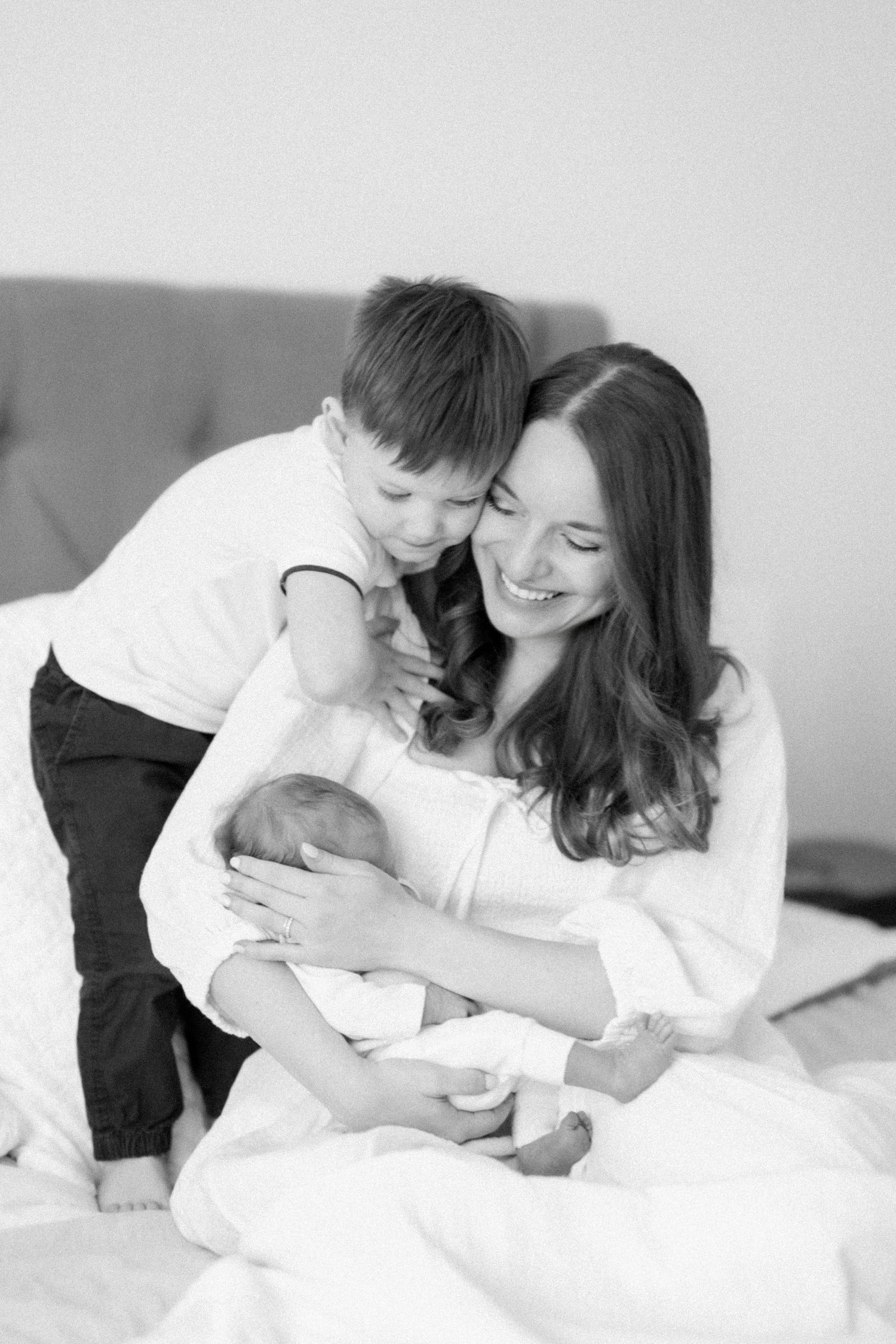 A tender black and white series of intimate family moments showing closeness and affection on white bedding.